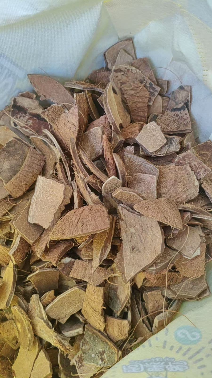 Raw coconut shell material in sack for charcoal production